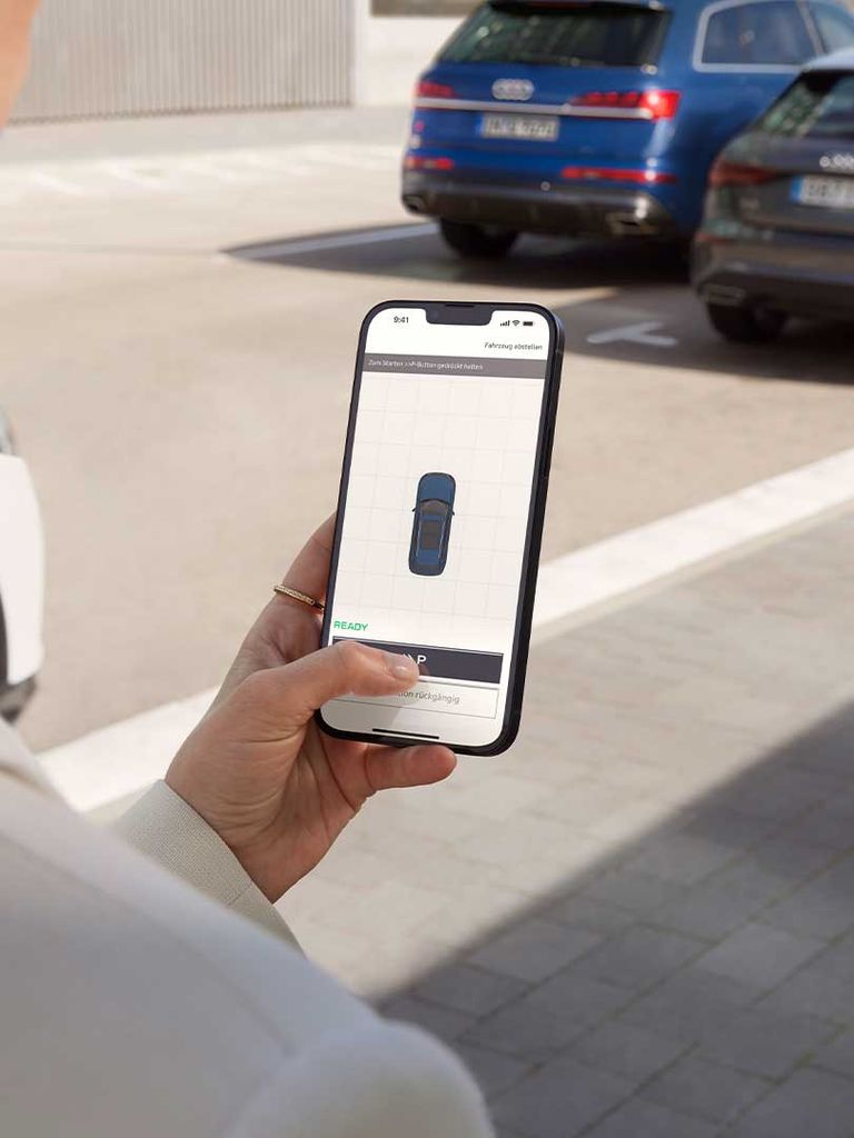 Woman holding a smartphone and operating the Audi Remote Parking Assistant